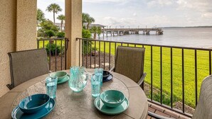 A covered outdoor dining area with a view of a water body and a pier. - First Floor Oceanfront Condominium in the Heart of (Saint Simons Island)