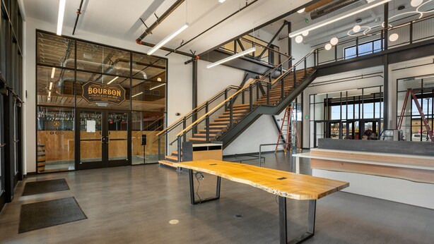 Een modern interieur met een houten bank, een trap en een glazen deur die leidt naar een barruimte.