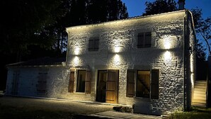 Een stenen gebouw met drie verlichte ramen en een houten deur.