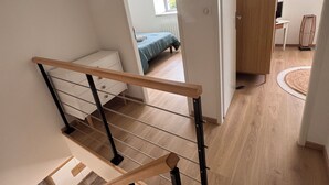 Een modern interieur met een houten trap, een bed in de aangrenzende kamer en een bureau met een computer.