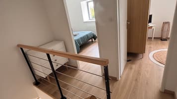 Ein modernes Interieur mit einer Holztreppe, einem Bett im angrenzenden Raum und einem Schreibtisch mit einem Computer.