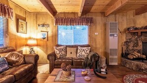 Un salón acogedor con paredes de madera, una chimenea y un sofá con cojines que dicen 'Stay Awake'.