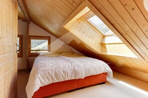 A bedroom with a sloped ceiling, a bed, and a window. - Ski-in/ski-out & foot of the slopes, 4th floor, view mountain/ski slopes, balcony (Méribel - Les Allues)