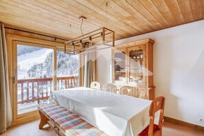 A room with a bed, a bench, a wooden cabinet, and a view of a snowy landscape. - 100m from resort center, 4th floor, view mountain/ski slopes, balcony, fireplace or stove, tv (Méribel - Les Allues)