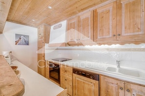 A kitchen with wooden cabinets, a built-in oven, and a dishwasher. - Ski-in/ski-out & foot of the slopes, 4th floor, view mountain/ski slopes, balcony (Méribel - Les Allues)