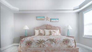 Ein Schlafzimmer mit einem Bett, zwei Nachttischen, einer Meerstern-Dekoration und einem Fenster.