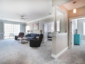 A spacious living room with a ceiling fan, a sofa, a coffee table, and a view through a sliding glass door to an outdoor area. - Havens 925 Recently Renovated and Great Location! (North Myrtle Beach)