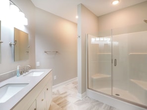 A modern bathroom with a glass-enclosed shower, a double sink vanity, and a large mirror. - Havens 925 Recently Renovated and Great Location! (North Myrtle Beach)