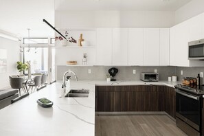 Una cocina moderna con armarios blancos, horno empotrado y microondas.