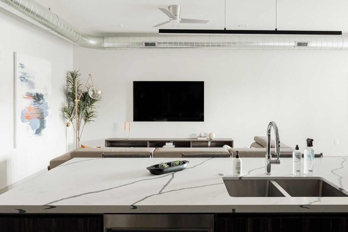 A modern kitchen with a marble countertop, a built-in sink, and a ceiling fan.