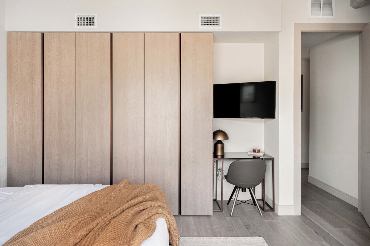A bedroom with a bed, a desk, a chair, a television, and a wardrobe.