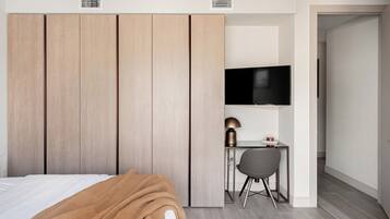 A bedroom with a bed, a desk, a chair, a television, and a wardrobe.