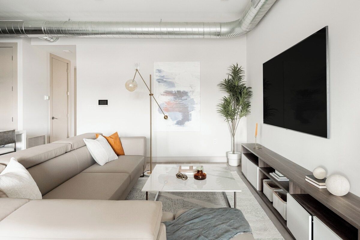 A modern living room with a sofa, coffee table, and a large flat-screen TV mounted on the wall.