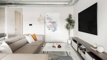 A modern living room with a sofa, coffee table, and a large flat-screen TV mounted on the wall.
