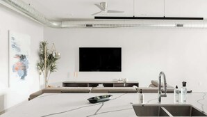Een moderne keuken met een groot eiland, ingebouwde apparatuur en een flatscreen televisie die boven het eiland is bevestigd.
