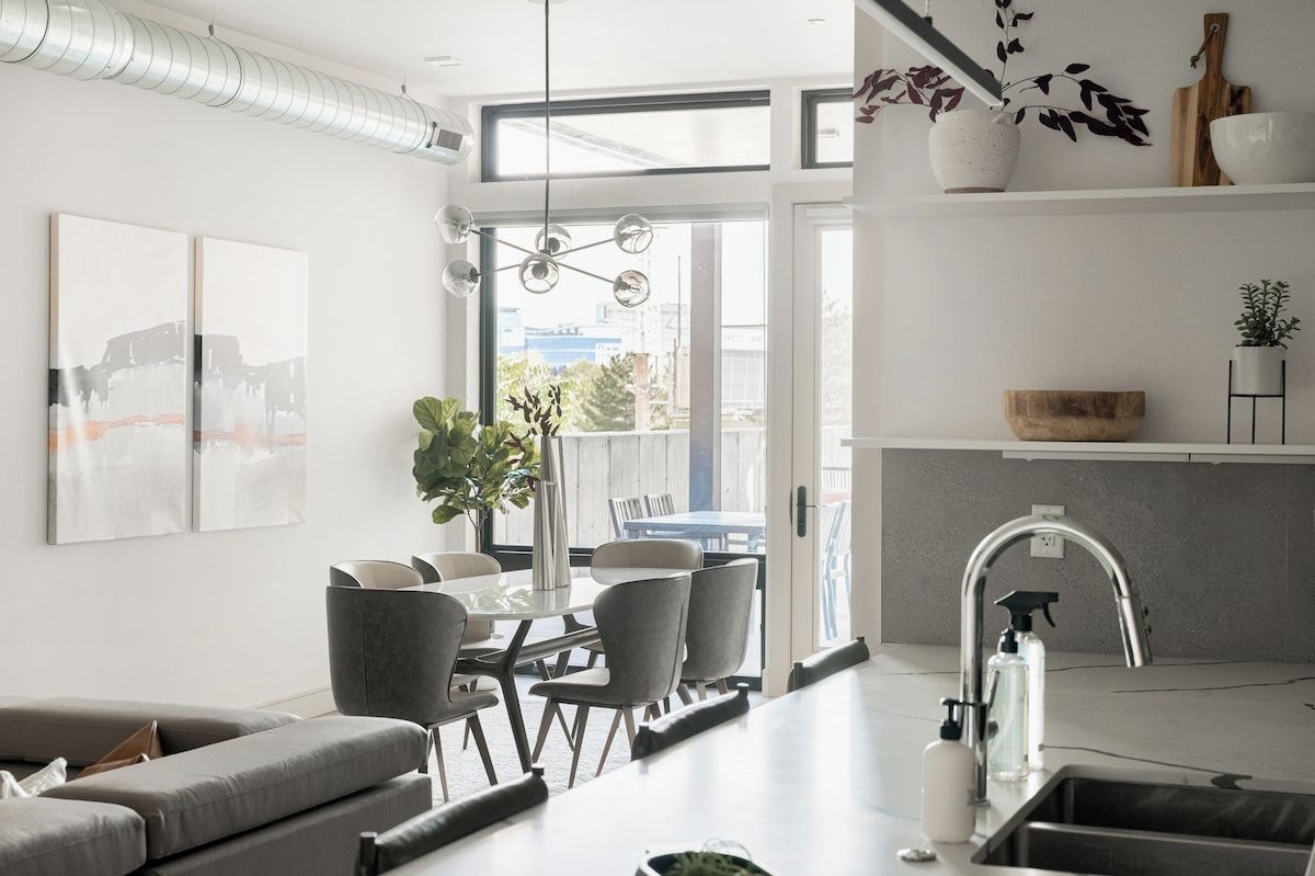 A modern kitchen with a built-in island, a dining area with a table and chairs, and a living room with a sofa.