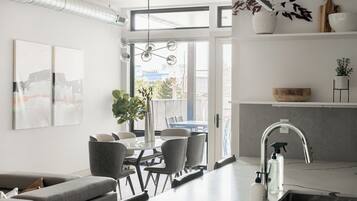 A modern kitchen with a built-in island, a dining area with a table and chairs, and a living room with a sofa.