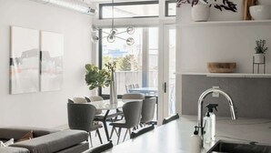 Een moderne keuken met een eetgedeelte, een inbouwoven en een groot raam dat zorgt voor daglicht.