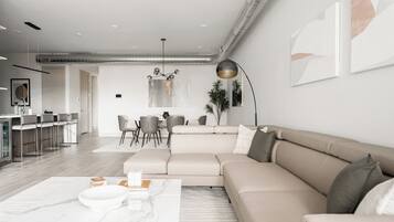Una sala de estar moderna con un sofá modular, una mesa de centro y un comedor con sillas y una mesa.