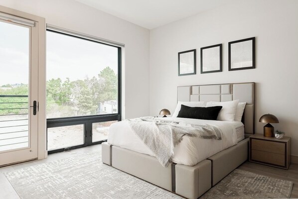 A bedroom with a bed, bedside tables, a window, and a view of greenery.