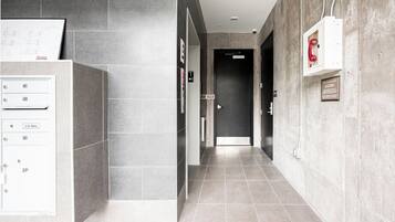 A hallway with a mail drop box, a door, and a fire alarm box.