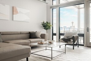 Uma sala de estar moderna com sofá, mesa de centro e vista da cidade por grandes janelas.
