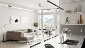 A modern living room with a sofa, coffee table, and a view of the city through large windows. - Modern Penthouse | Private Skyline Balcony (Denver)