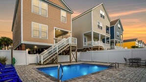 Ein zweistöckiges Haus mit Swimmingpool, überdachter Terrasse und weißem Zaun.