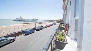 A coastal road with parked cars, a beach, and a pier in the background. - Apartment - Sleeps 4 - Balcony - Sea View (Eastbourne)