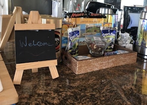 A welcome sign on a chalkboard, a tray with snacks, and various packaged goods on a kitchen counter. - Apartment - Sleeps 4 - Balcony - Sea View (Eastbourne)