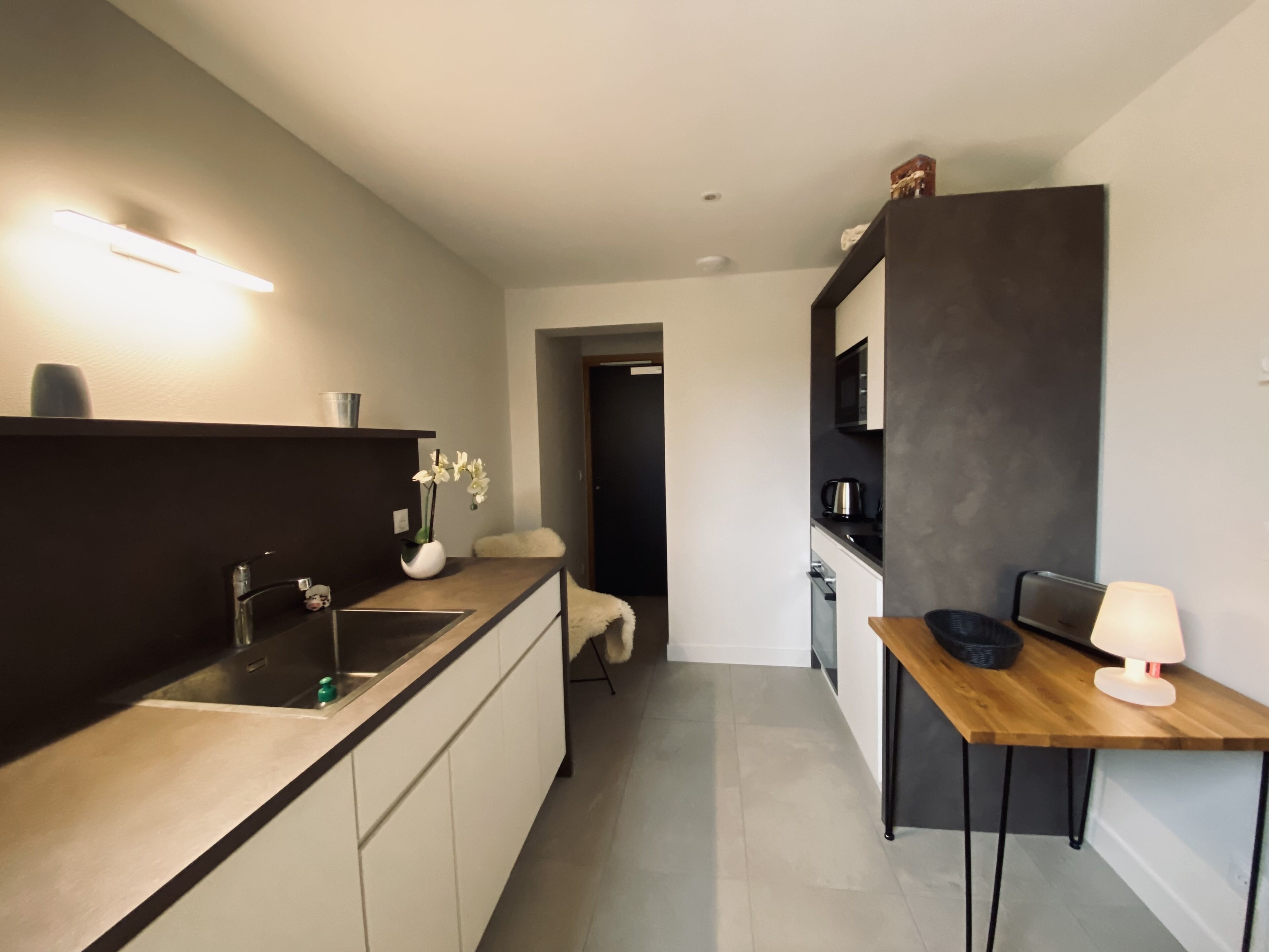 Eine moderne Küche mit Einbauofen, Spüle und einem Holztisch mit Lampe.