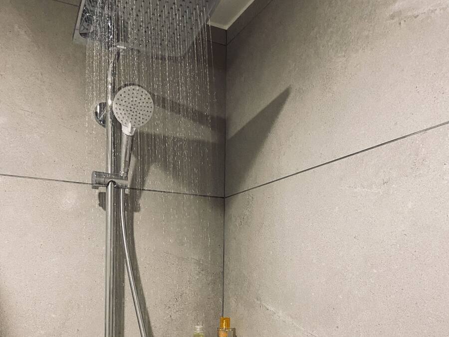 A shower with a glass shelf holding two bottles.