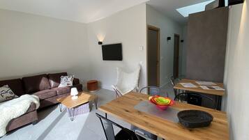 Ein modernes Wohnzimmer mit einer Couch, einem Couchtisch und einem Esstisch mit Stühlen.