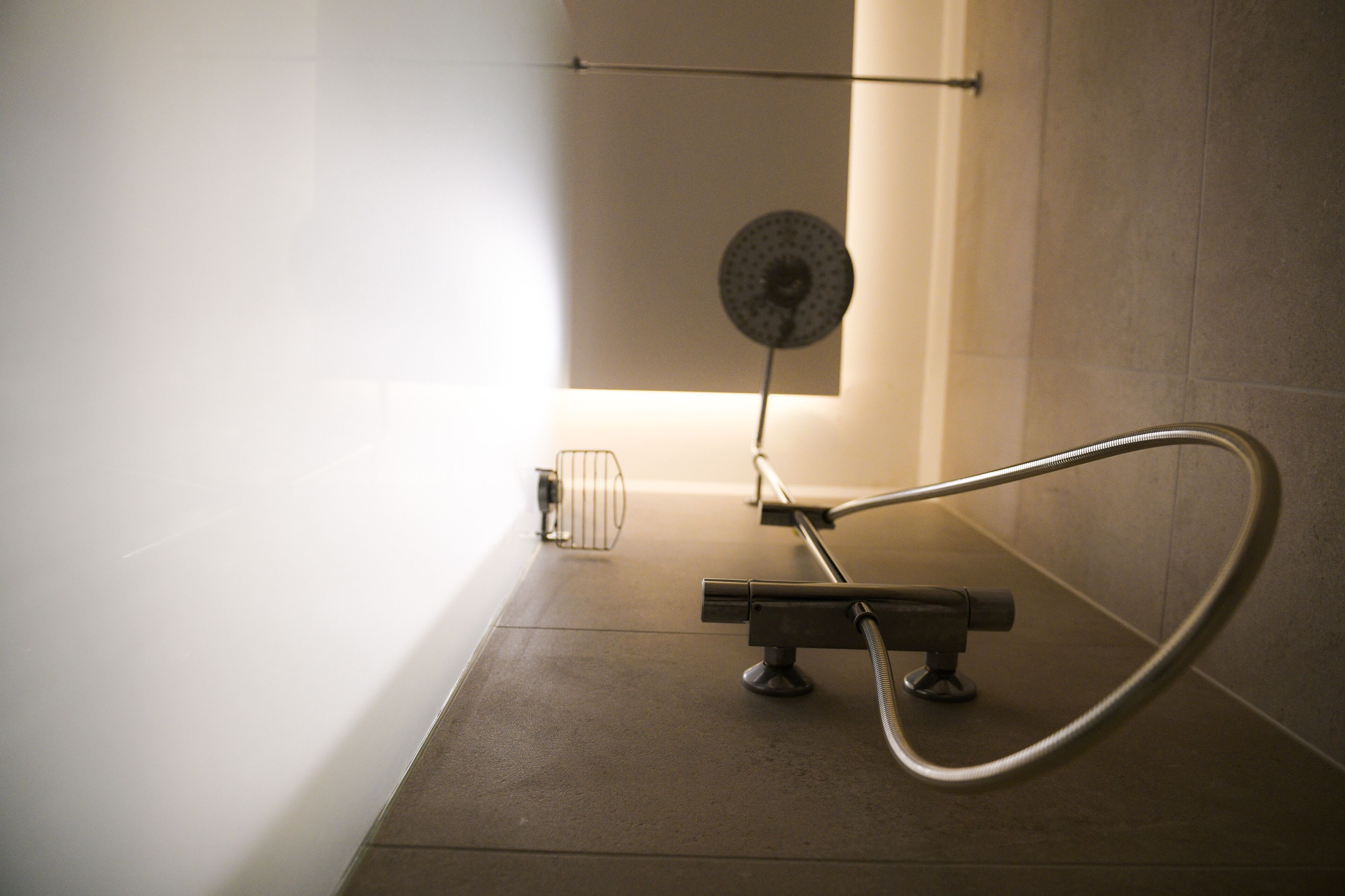 Un baño moderno con ducha, perchero y lámpara de pared.