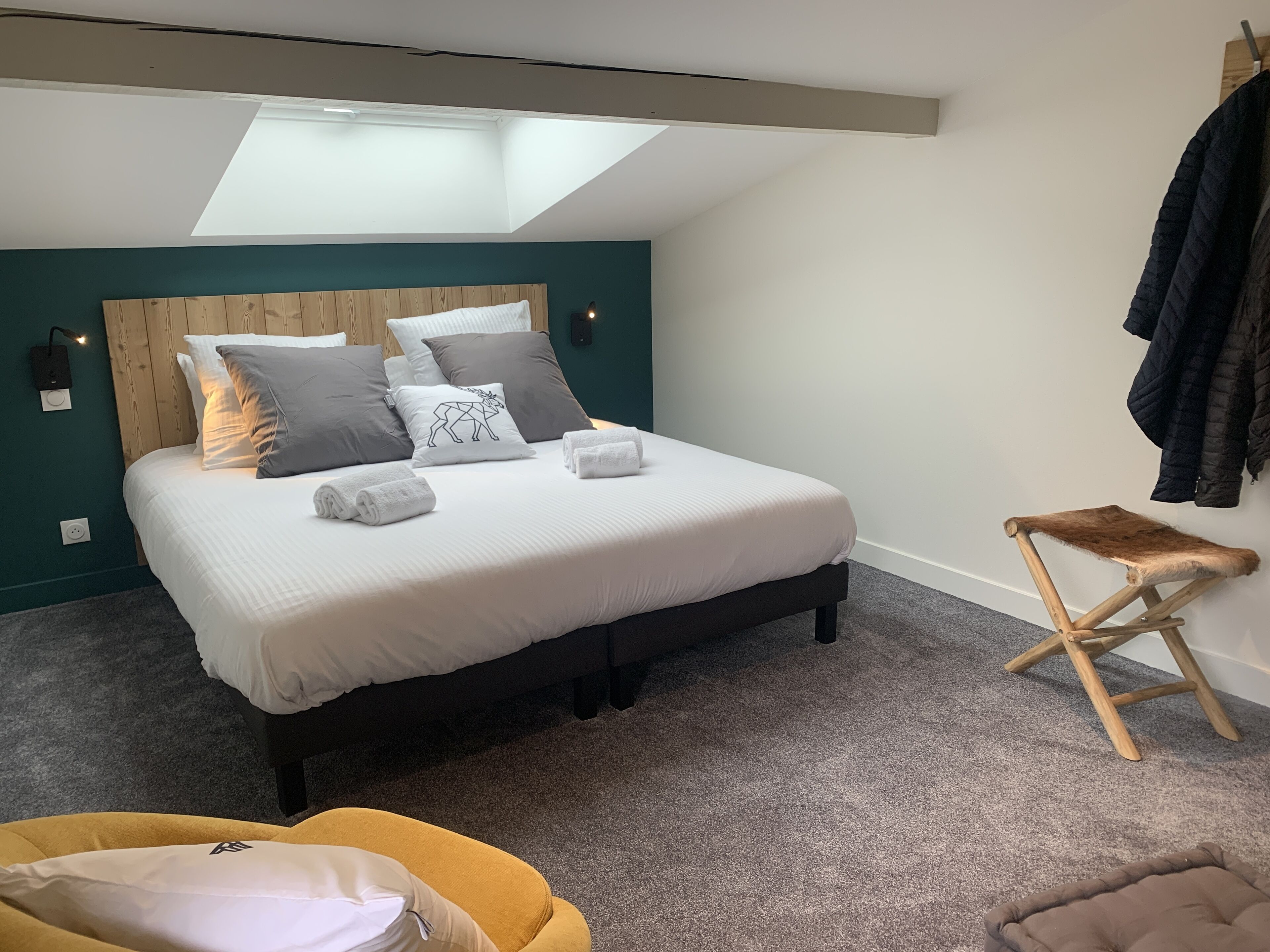 A bedroom with a bed, a bench, a small stool, and a ceiling light.