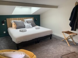 Un dormitorio con cama, un banco, un taburete pequeño y una lámpara en el techo.