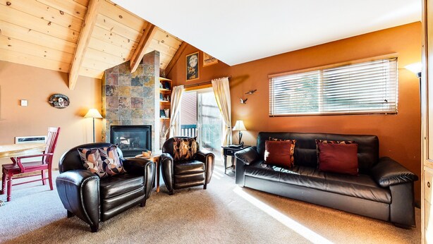 A cozy living room with a fireplace, leather sofas, and a stone wall. - Mammoth View Villas 3 Walk to Village Gondola, Cozy Mountain Cabin in Forest Setting by RedAwning (Mammoth Lakes)
