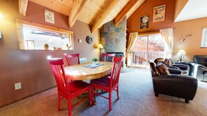 A cozy room with a wooden dining table, red chairs, a fireplace, and a sofa. - Mammoth View Villas 3 Walk to Village Gondola, Cozy Mountain Cabin in Forest Setting by RedAwning (Mammoth Lakes)