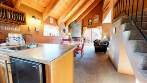A kitchen with a sink, a dishwasher, and a dining area with a table and chairs. - Mammoth View Villas 3 Walk to Village Gondola, Cozy Mountain Cabin in Forest Setting by RedAwning (Mammoth Lakes)