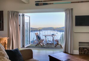 Un salón con vistas a un cuerpo de agua, una mesa con sillas y un sofá.