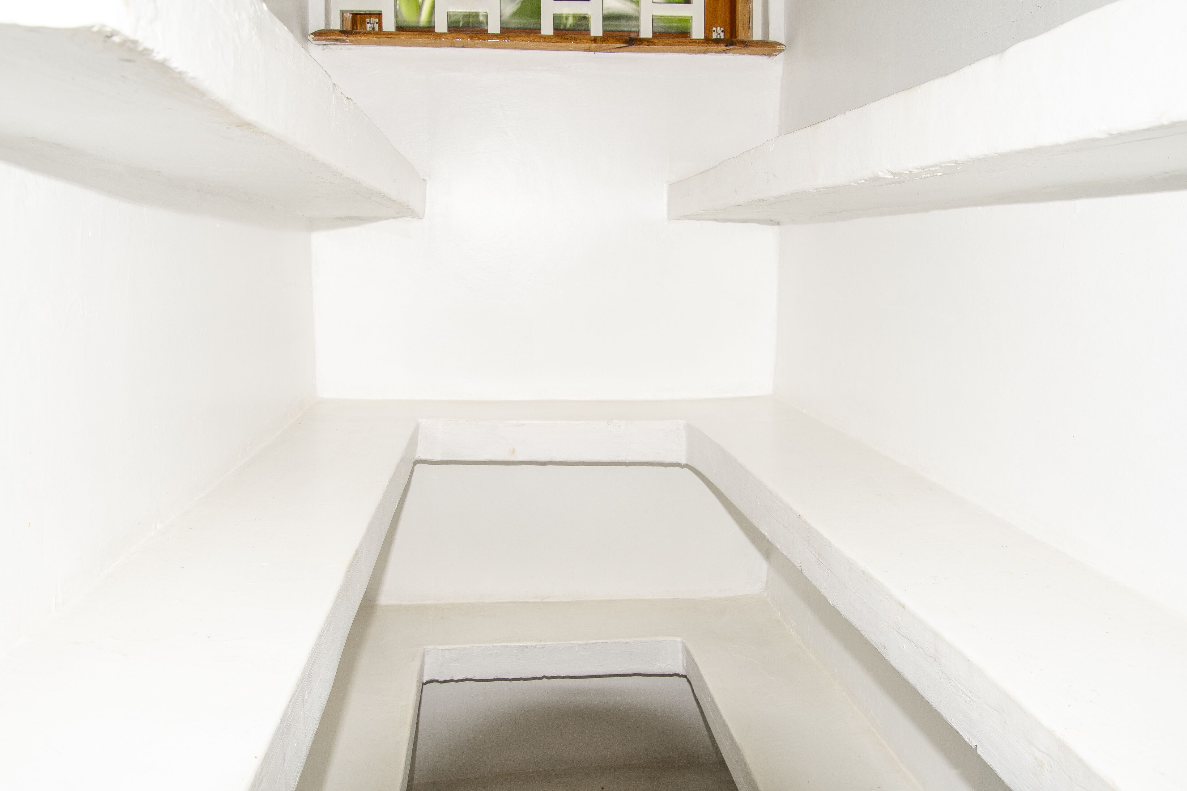 A white, empty room with a small window and a door.