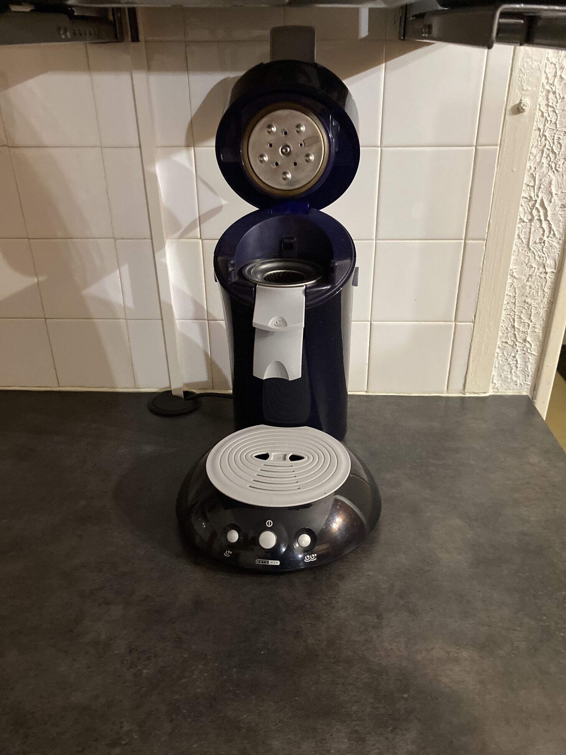 A coffee maker on a kitchen counter with a tiled backsplash.