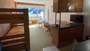 Une cuisine de taille réduite, dotée de meubles en bois et d’un coin repas offrant une vue sur les montagnes.