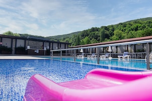 A swimming pool with a pink slide, lounge chairs, and a building with a roofed area.