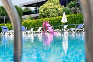 A swimming pool with lounge chairs and a pink slide. - Hotel Vela Verde (Yalova)