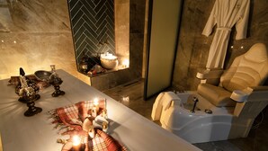 A luxurious bathroom with a large bathtub, a vanity with a mirror, and a robe hanging on the wall. - Hotel Vela Verde (Yalova)