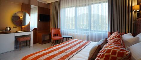 A hotel room with a bed, a desk, a chair, a TV, and a window with curtains.