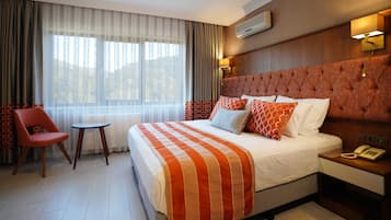 Una habitación de hotel con una cama grande, una silla, una mesita y un teléfono junto a la cama.