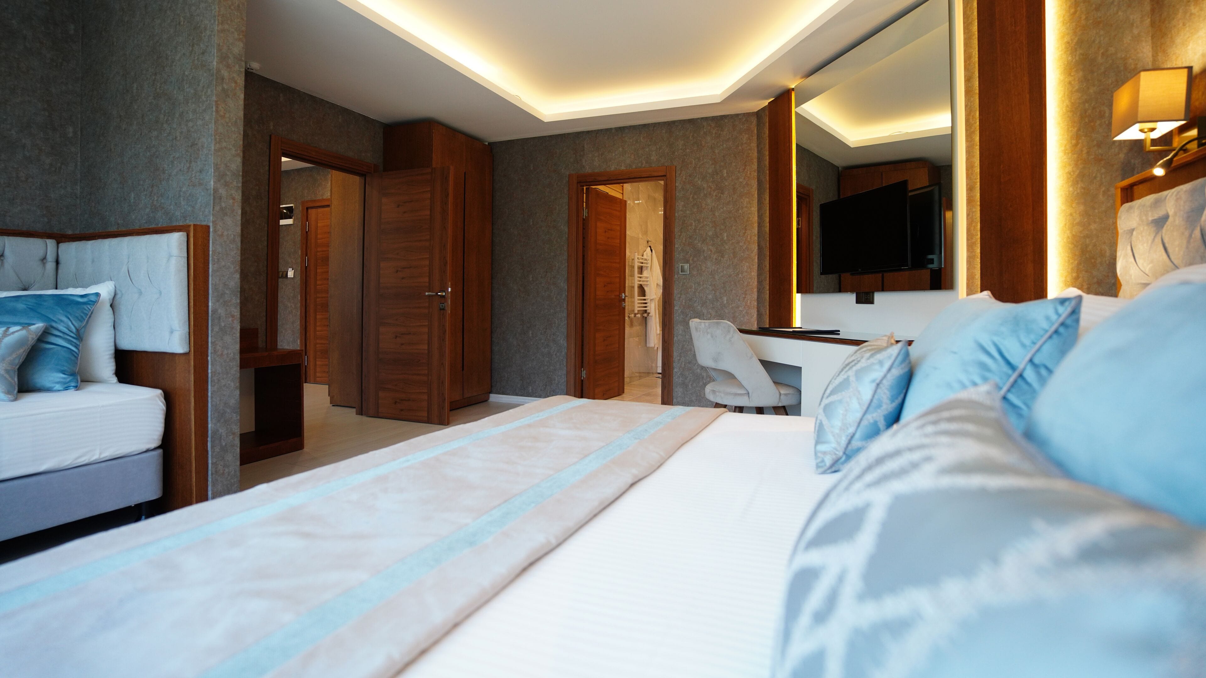A modern hotel room with a large bed, a desk, and a television.