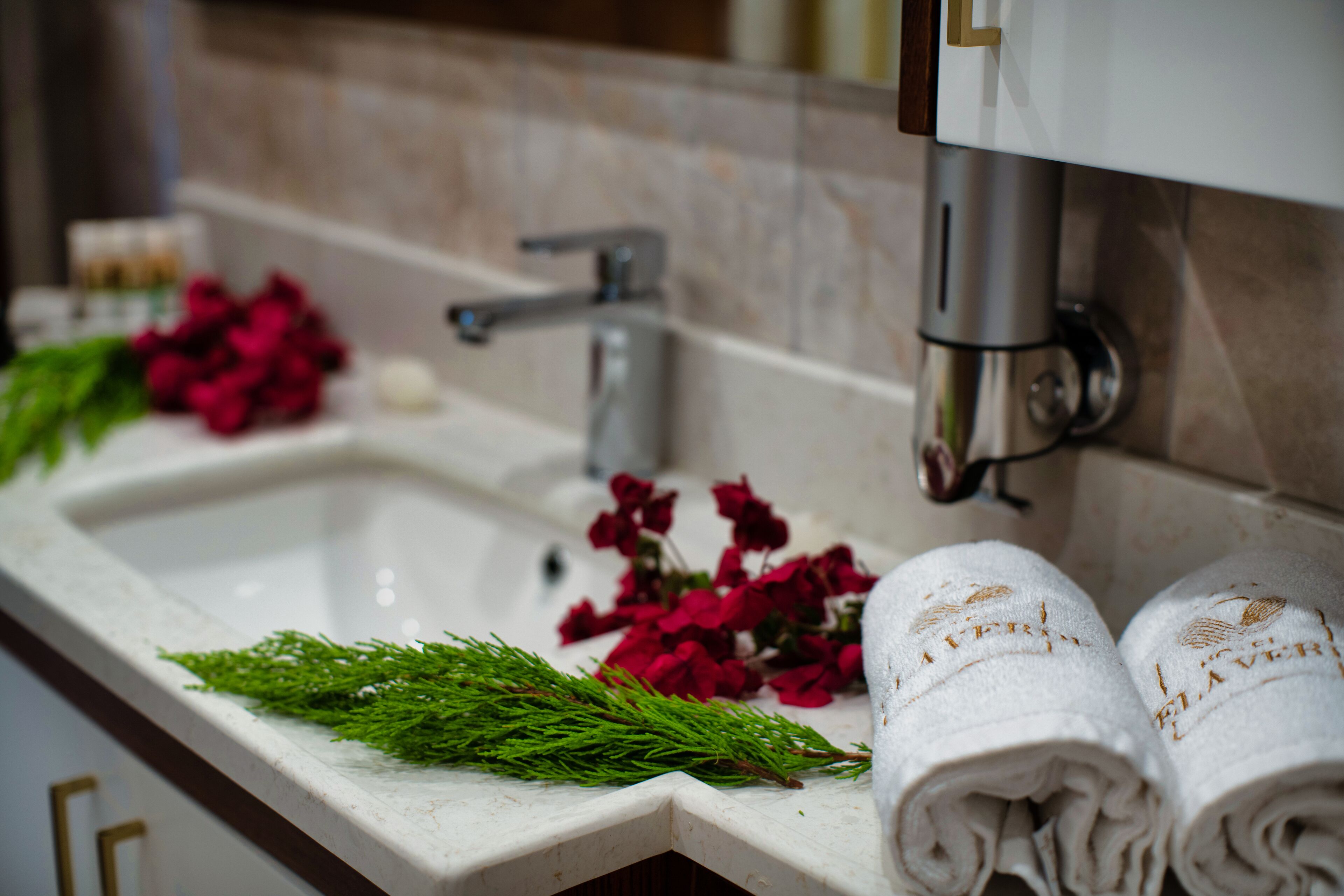 A bathroom sink with a mirror, a faucet, and a towel rack with towels.